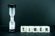 A picture of an egg timer/hourglass, next to a set of scrabble tiles that say 